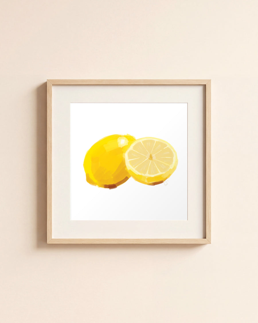 Lemons giclée art print in a light oak frame with a white mat, hanging on a cream wall