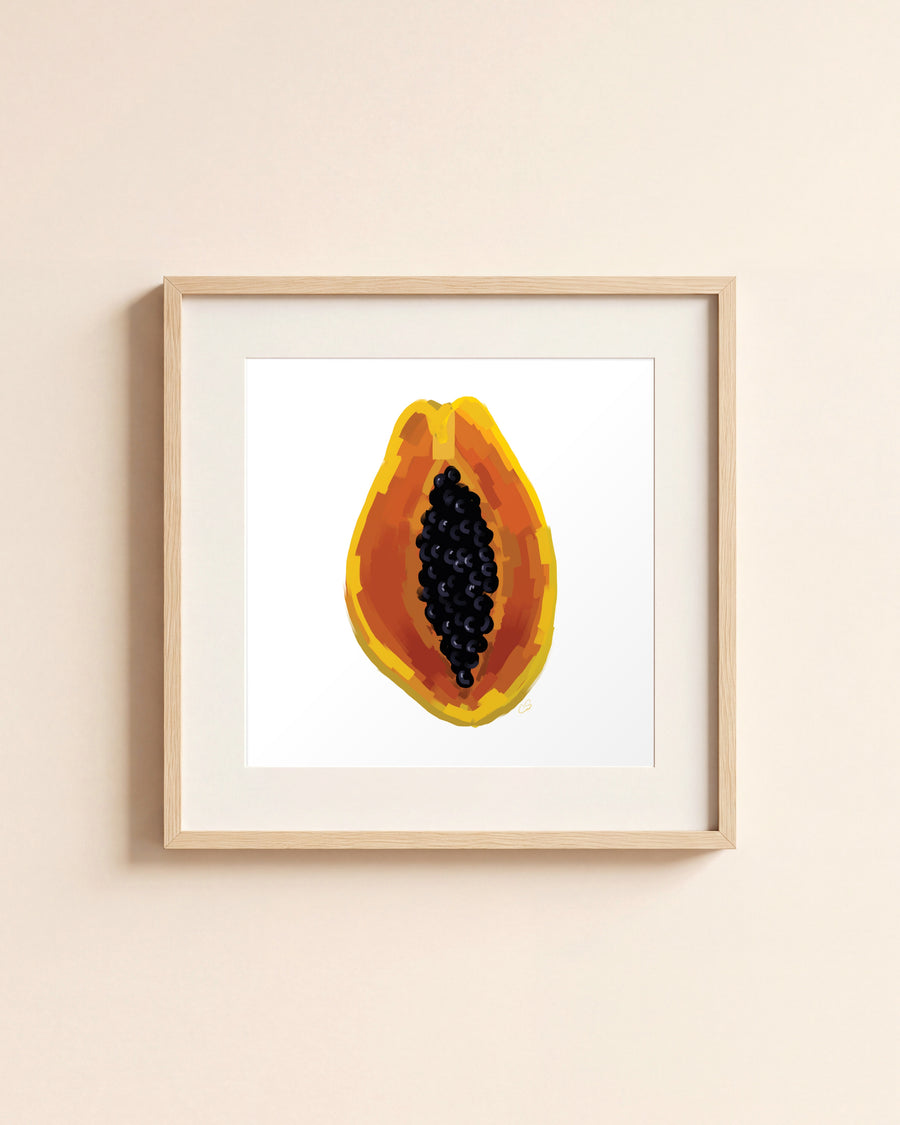 Papaya giclée art print in a light oak frame with a white mat, hanging on a cream wall